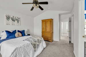 Bedroom with vaulted ceiling, light colored carpet, and ceiling fan