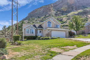 Traditional-style house with an attached garage, a mountain view, a front lawn, brick siding, and concrete driveway