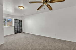 Carpeted spare room with baseboards and ceiling fan