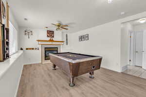 Rec room with billiards table, a ceiling fan, wood finished floors, and a tile fireplace