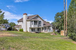 Back of house featuring a shed, a yard, a chimney, a shingled roof, and french doors