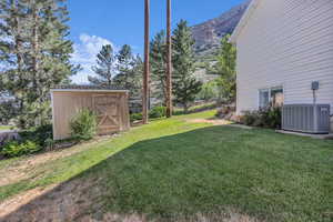 View of green lawn featuring a shed and a mountain view