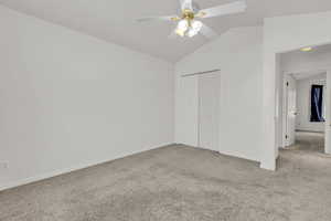 Unfurnished bedroom with carpet flooring, vaulted ceiling, a closet, and ceiling fan