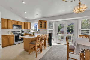 Kitchen with black microwave, gas range gas stove, lofted ceiling, a breakfast bar area, and glass insert cabinets