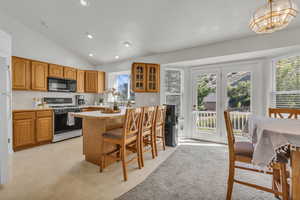 Kitchen with white gas range oven, black microwave, lofted ceiling, light countertops, and glass insert cabinets