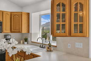 Kitchen featuring light countertops, glass insert cabinets, a mountain view, and brown cabinetry