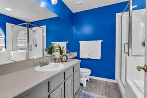 Bathroom featuring a shower stall, vanity, and wood finished floors