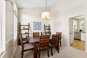 Dining room with light colored carpet and a towering ceiling