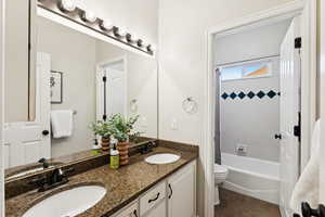 Full bathroom featuring double vanity, shower / bath combo, and tile patterned flooring