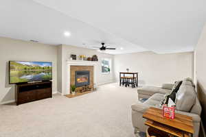 Carpeted living room featuring ceiling fan, a fireplace, and recessed lighting