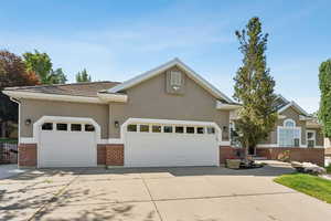 View of front facade featuring brick siding, an attached garage, driveway, stucco siding, and a tiled roof