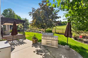 Fenced backyard featuring a pergola, a grill, a patio, and a deck