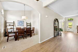 Dining space featuring arched walkways, wood finished floors, a chandelier, and crown molding