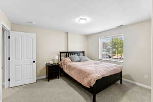 Bedroom with light colored carpet and a textured ceiling