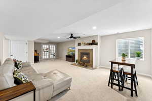 Living room featuring light carpet, a tile fireplace, a ceiling fan, and recessed lighting