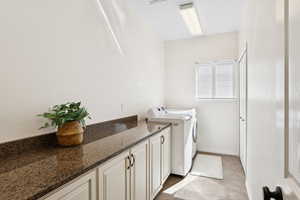 Washroom featuring washer and dryer, light tile patterned floors, and cabinet space