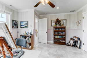 Office with ceiling fan, a wainscoted wall, crown molding, and wallpapered walls