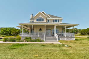Farmhouse-style home featuring a chimney, a front yard, covered porch, and roof with shingles
