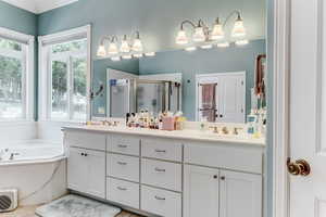 Full bathroom with a stall shower, double vanity, a garden tub, and crown molding