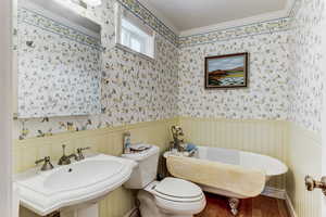 Bathroom with wood finished floors, a freestanding tub, wainscoting, and crown molding