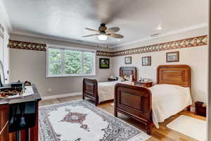 Bedroom featuring light wood-type flooring, crown molding, and ceiling fan
