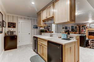 Kitchen featuring light brown cabinetry, stainless steel microwave, ornamental molding, open floor plan, and beverage cooler