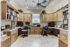 Office with rail lighting, built in desk, ornamental molding, and a ceiling fan