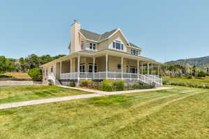 Farmhouse inspired home featuring a porch, a chimney, and a front lawn