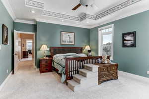 Carpeted bedroom with ornamental molding, a tray ceiling, recessed lighting, and a ceiling fan