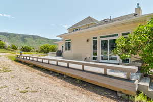 Back of property with a deck with mountain view and a shingled roof