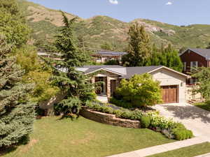 Aerial of Home nestled in foothills, with beautiful professional landscaping and heated driveway