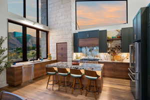 Kitchen with stainless steel appliances, light stone countertops, light wood finished floors, and a breakfast bar