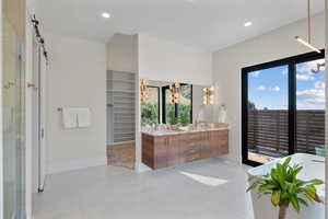 Bathroom featuring double vanity, a shower stall, a soaking tub, a spacious closet, and recessed lighting