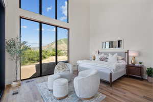 Bedroom featuring a high ceiling, a mountain view, access to outside, and wood finished floors