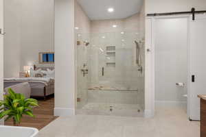 Ensuite bathroom featuring a shower stall and baseboards