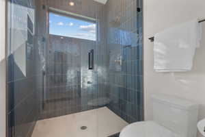 Full bath featuring toilet and tiled shower