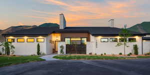 View of front facade with a chimney, a mountain view, and stucco siding