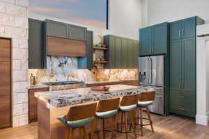 Kitchen with stainless steel fridge, tasteful backsplash, a kitchen island, a breakfast bar area, and a high ceiling