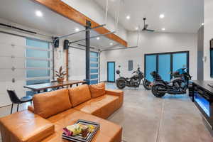 Living area featuring electric panel, finished concrete floors, ceiling fan, recessed lighting, and high vaulted ceiling