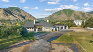 View of front of property featuring a chimney, asphalt driveway, a garage, a mountain view, and a front yard