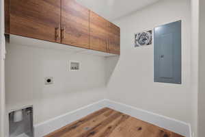 Laundry room with electric panel, cabinet space, hookup for a washing machine, wood finished floors, and hookup for an electric dryer