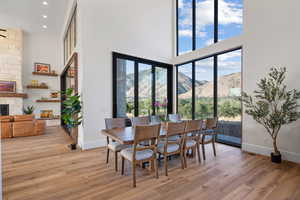 Dining area featuring a high ceiling, a stone fireplace, light wood finished floors, recessed lighting, and a mountain view