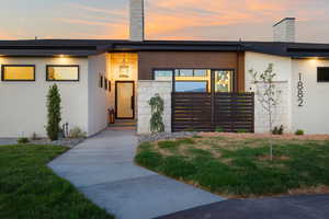 View of front of property with a chimney, a yard, and stucco siding