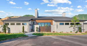 View of front of home with a chimney, a mountain view, and stucco siding
