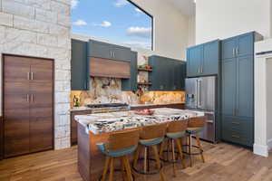 Kitchen with high quality fridge, stove, decorative backsplash, a center island, and light wood-style floors