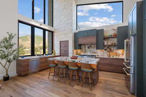 Kitchen with appliances with stainless steel finishes, light wood finished floors, a kitchen island, a kitchen breakfast bar, and a high ceiling