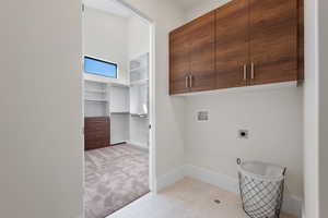 Laundry room with cabinet space, washer hookup, electric dryer hookup, and light colored carpet