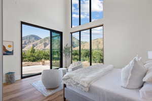 Bedroom featuring access to exterior, a mountain view, wood finished floors, and a high ceiling