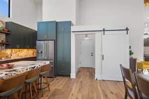 Kitchen featuring high end fridge, a high ceiling, a barn door, backsplash, and open shelves