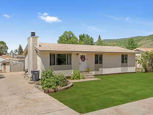 Single story home featuring a front lawn, a mountain view, a chimney, and roof with shingles